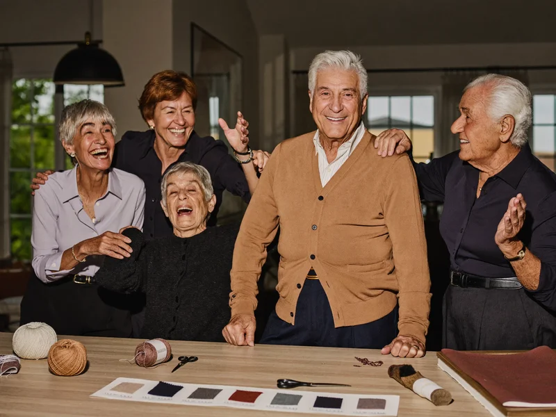 Gruppo di anziani che ride mentre lavora insieme a un tavolo condiviso.